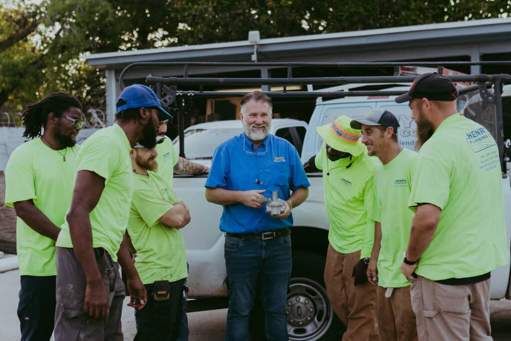 Todd Reed leading a discussion with his Henry Plumbing team at an outdoor worksite