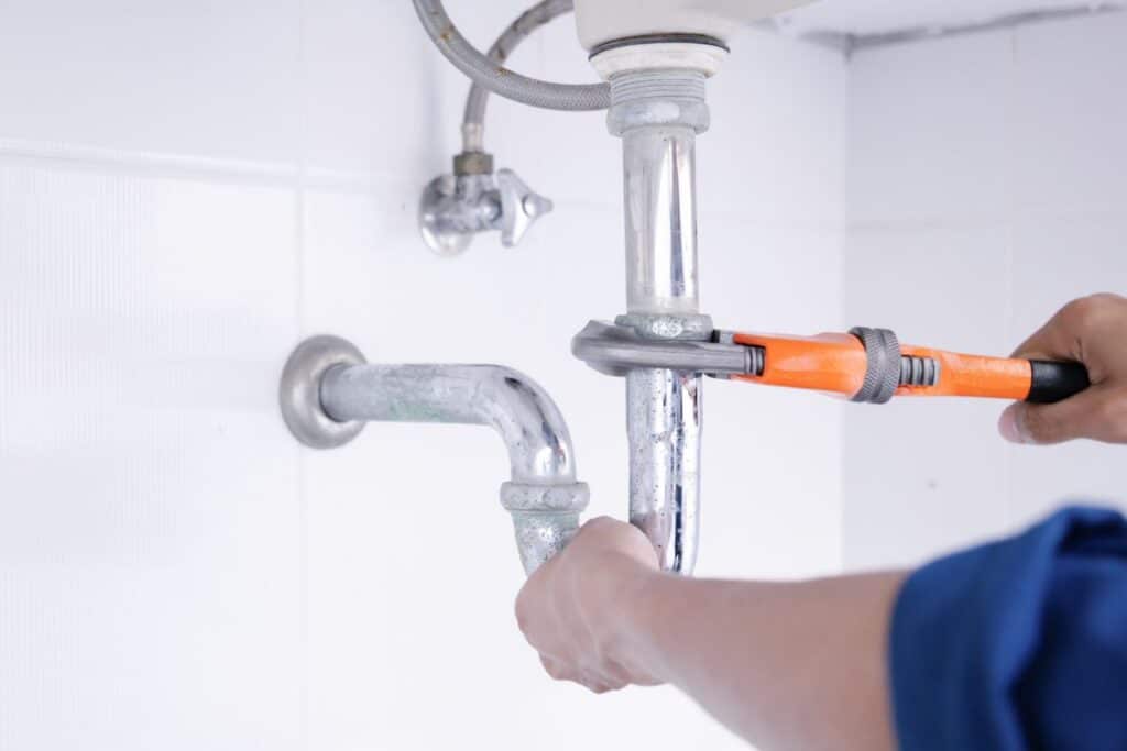 “A close-up view of a plumbing P-trap installation beneath a sink, designed to prevent sewer gases from entering the home while allowing wastewater to flow properly.