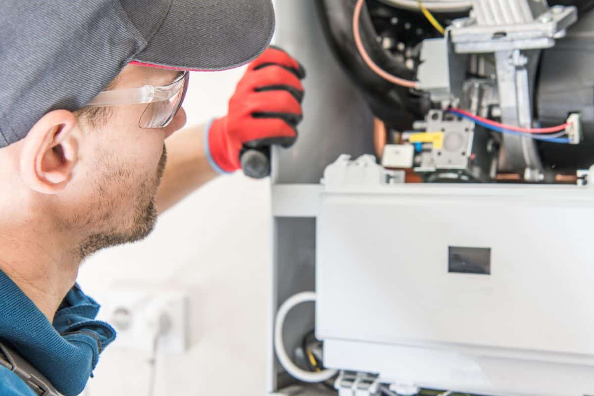 Plumbing technician repairing under-sink plumbing connections