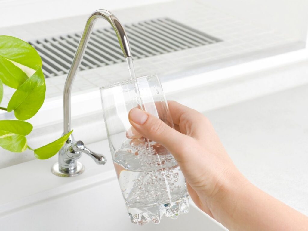 Filling glass with filtered drinking water from kitchen faucet