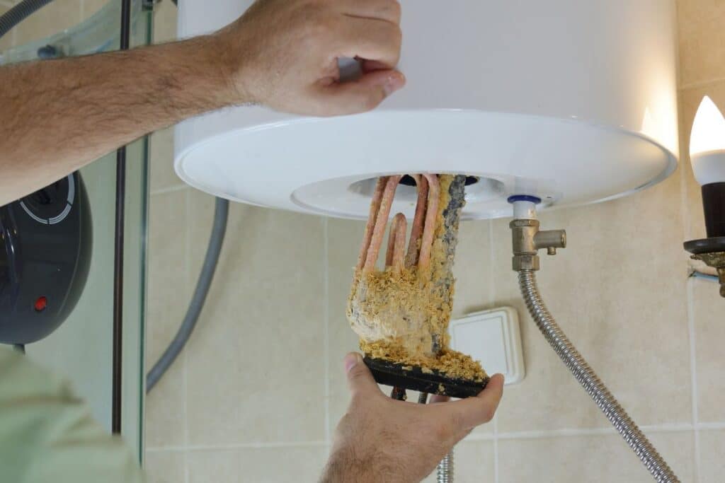 A pair of hands working on a water heater flushing the water heater in Savannah GA