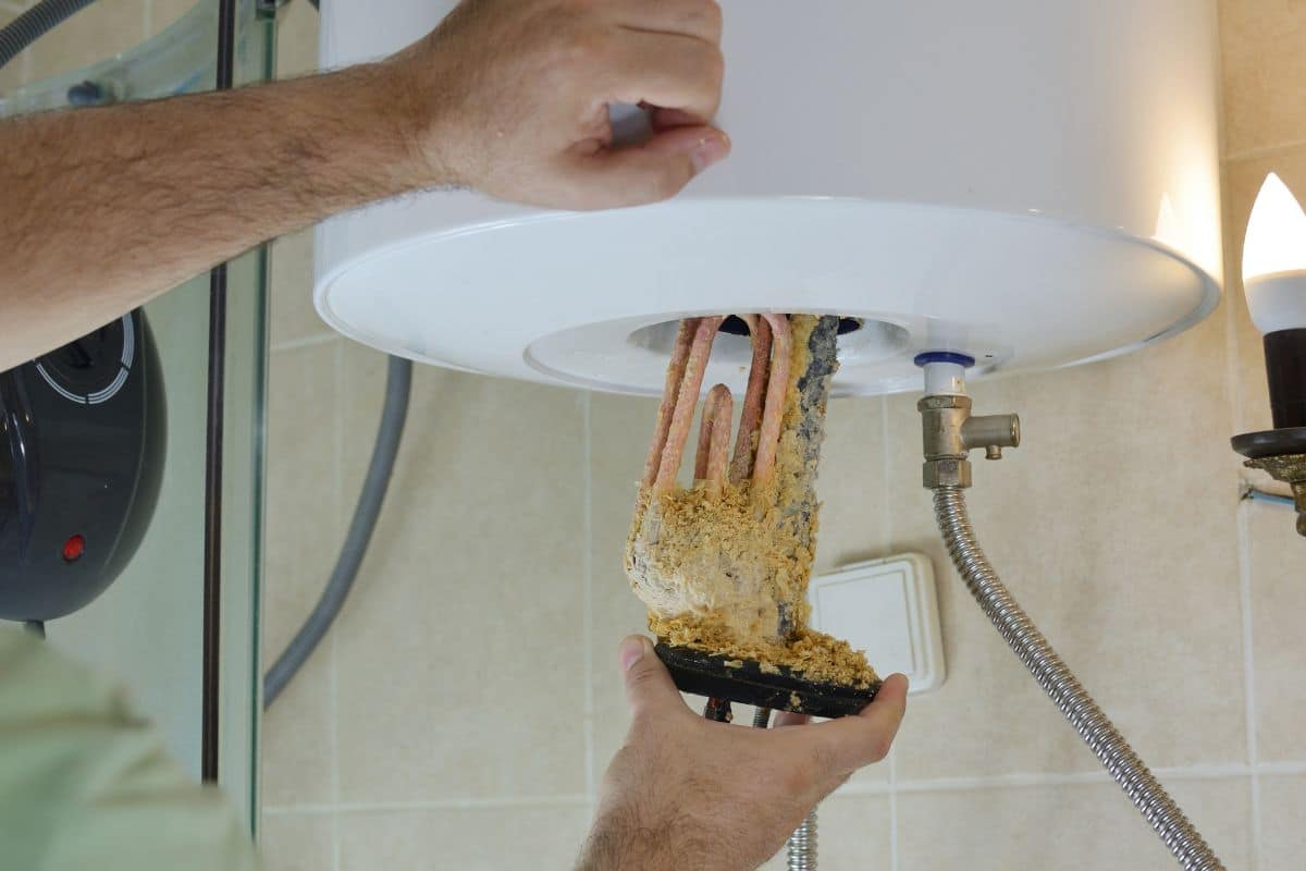 A pair of hands working on a water heater flushing the water heater in Savannah GA